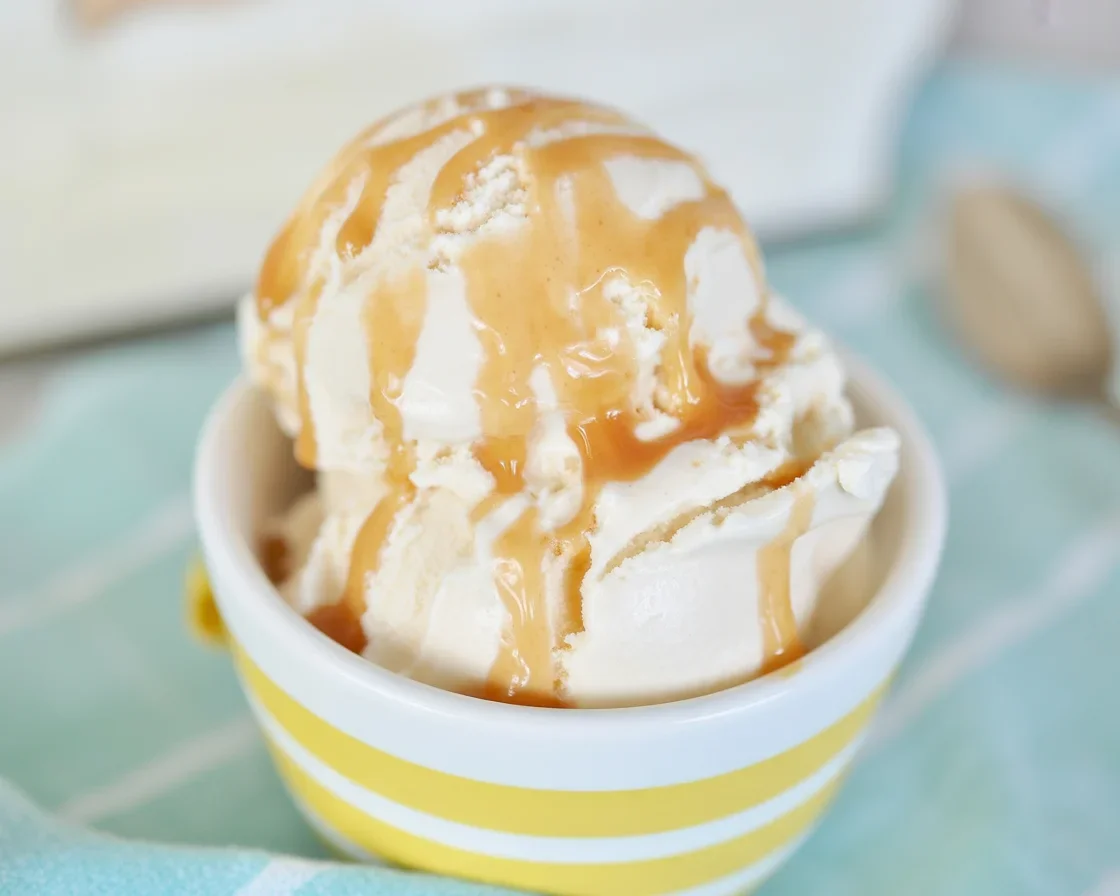 Delicious salted caramel sea salt ice cream in a bowl with a scoop and caramel drizzle.