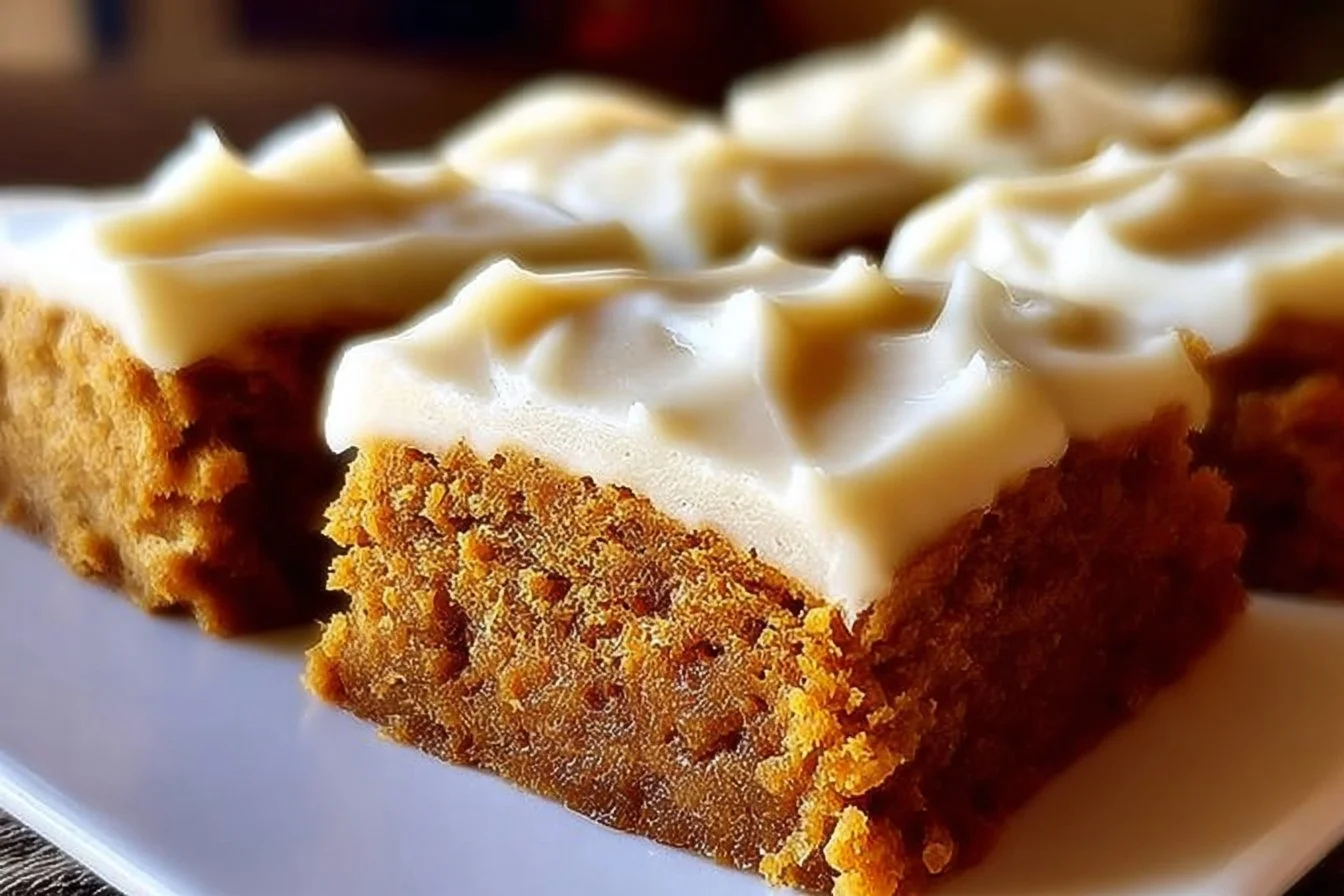 Delicious old-fashioned pumpkin bars with cream cheese frosting on a plate.